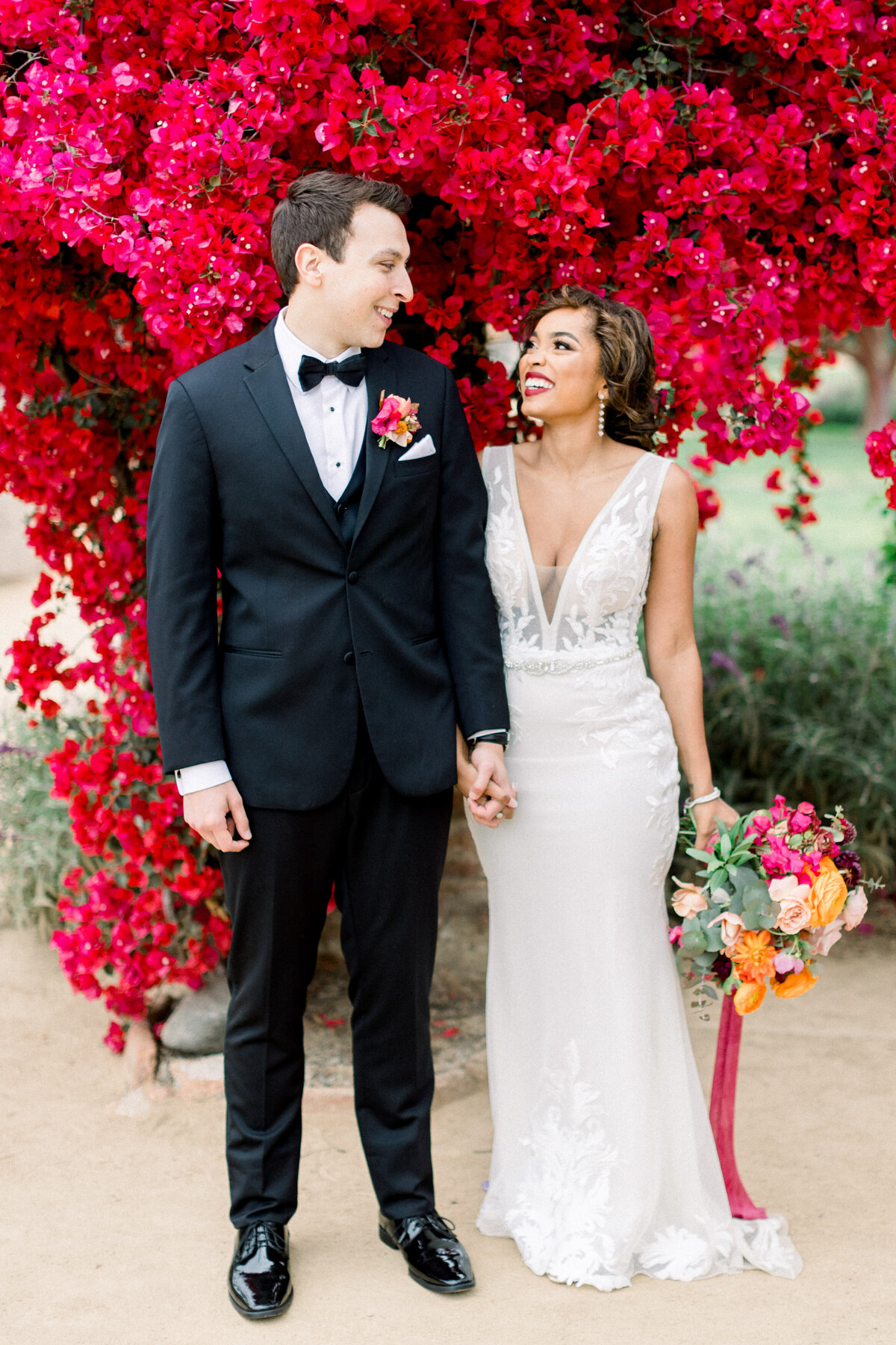 Laughing beneath a wall of crimson bougainvillea