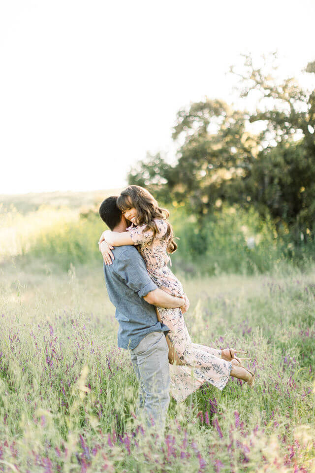 Lifted off her feet in a meadow of spring wildflowers