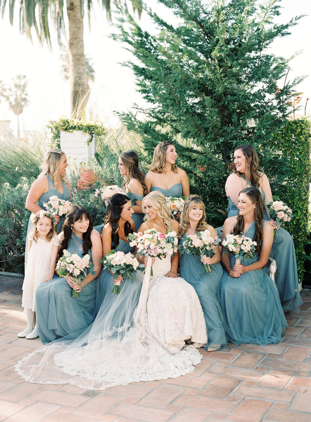 The bridal party in dusty blue, a flower girl tucked in at the edge