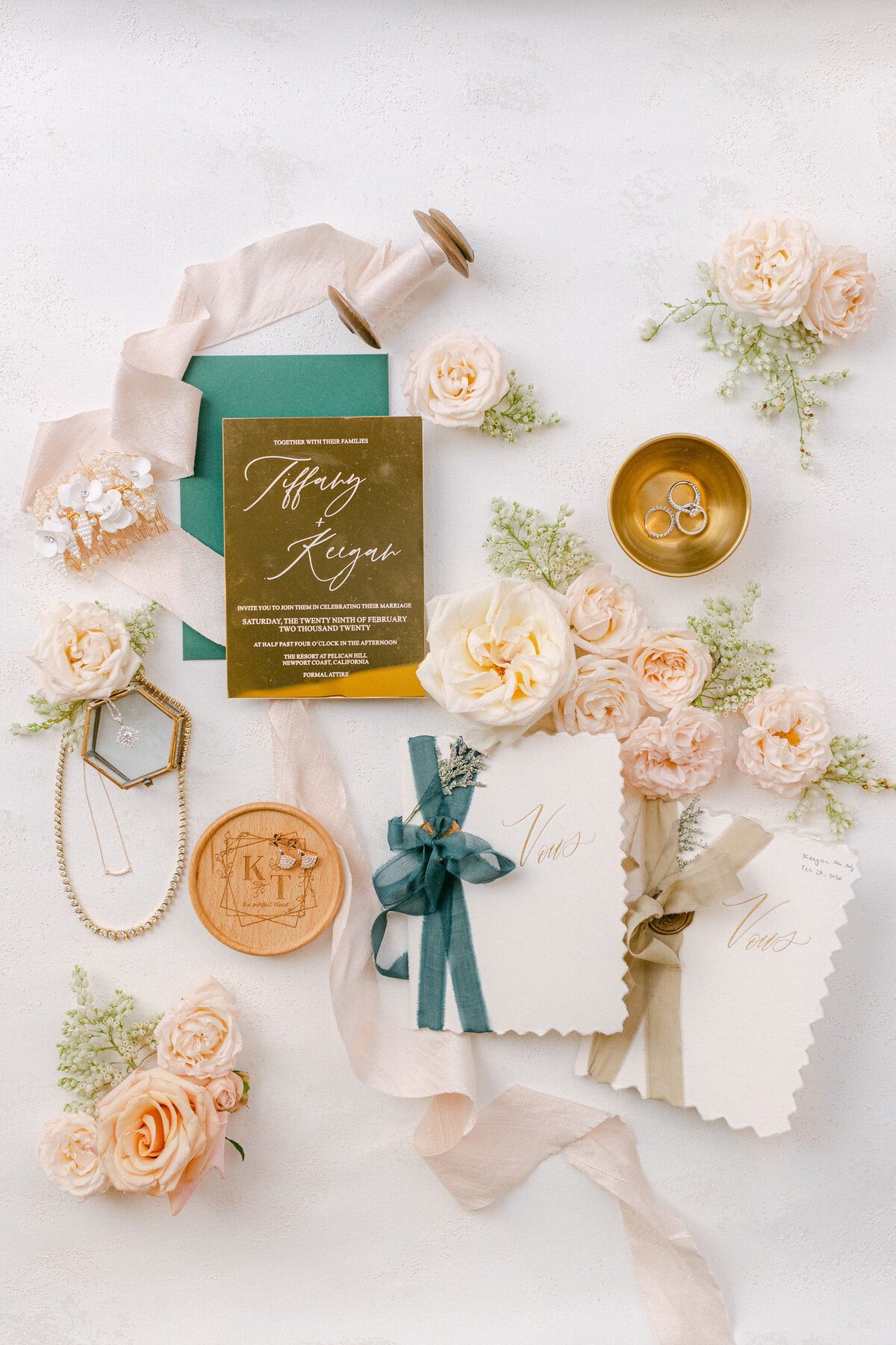 A mirrored gold invitation to Pelican Hill, vow books ribboned in teal