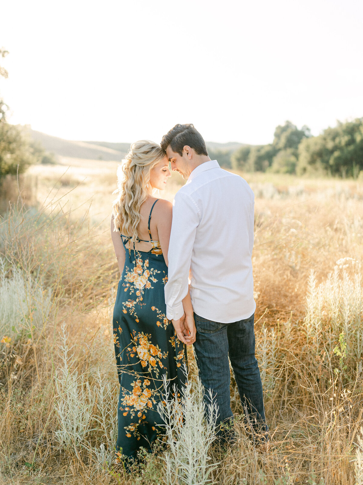 Foreheads together in the dry summer grass, her silk dress printed with marigolds