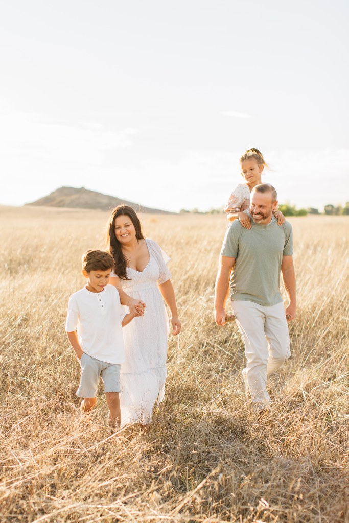 The Hickmans walking through a golden field at sunset