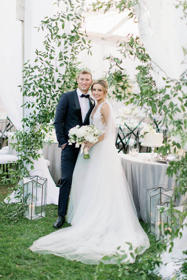 Under an arch of smilax inside the tent, the cake waiting behind them