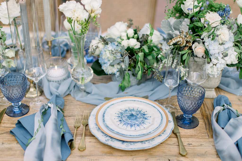 Blue and white china, French blue napkins and white roses on a raw wood table