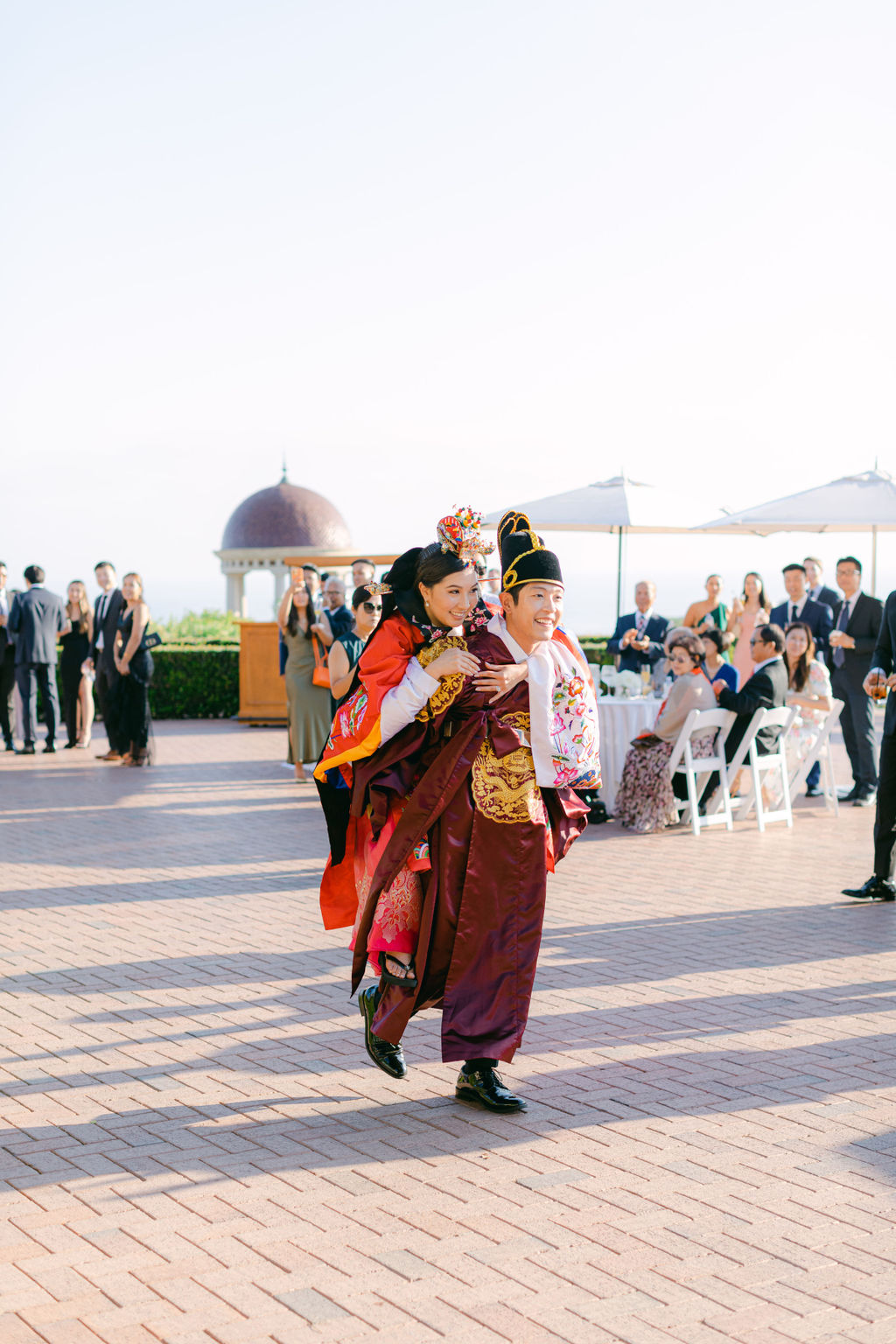 The groom carrying the bride on his back during the paebaek at Pelican Hill, the rotunda behind them