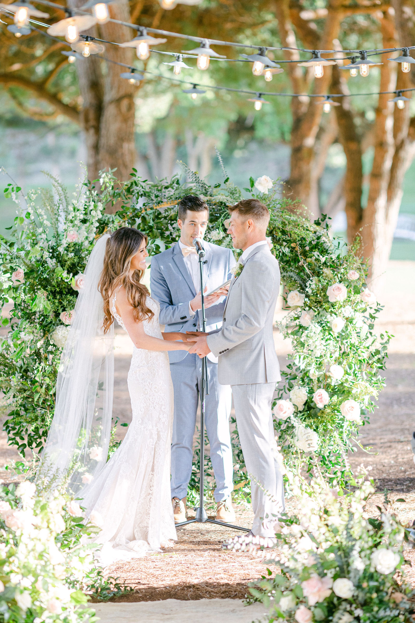 Vows beneath a greenery and white floral arch