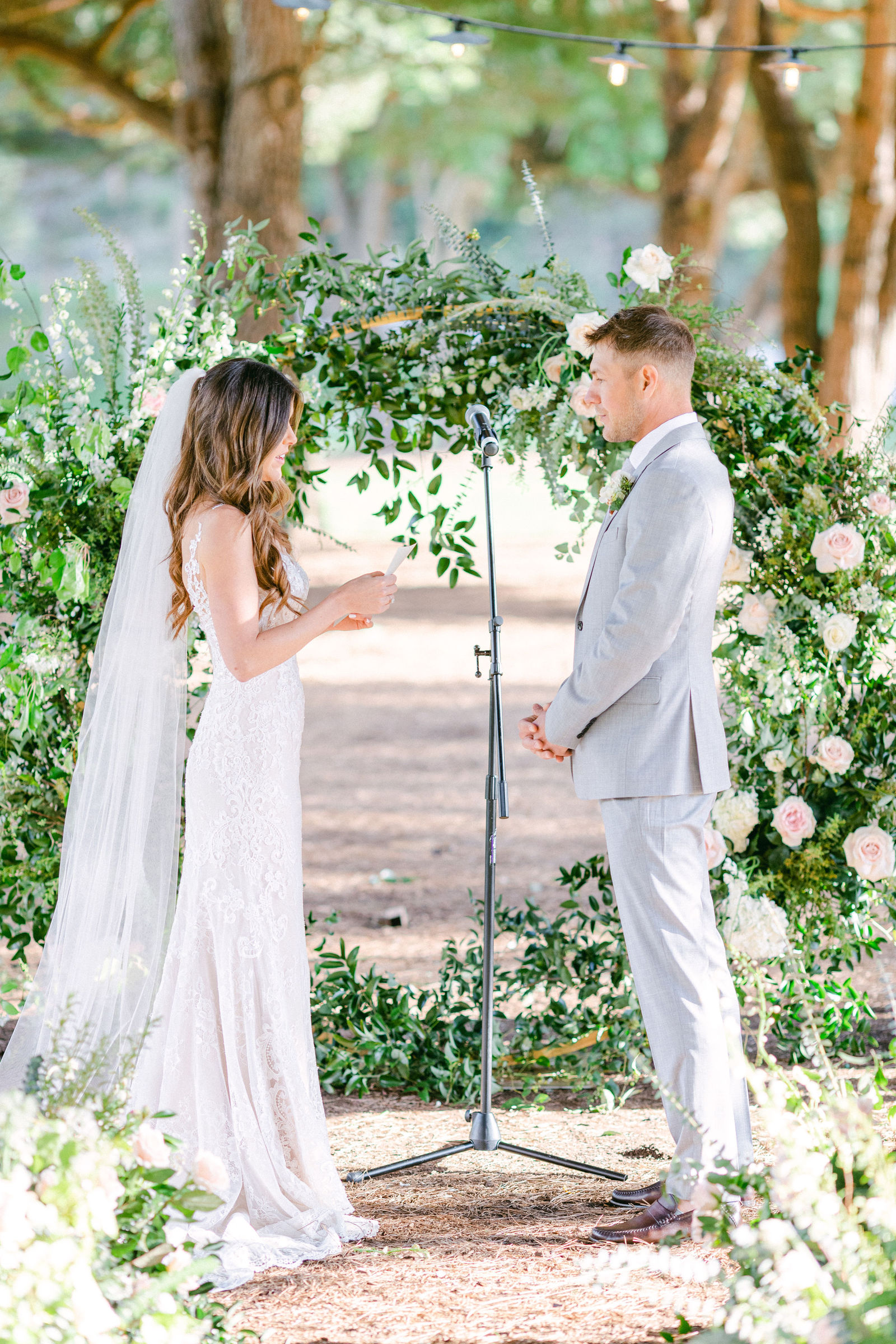 Vows beneath a greenery and white floral arch