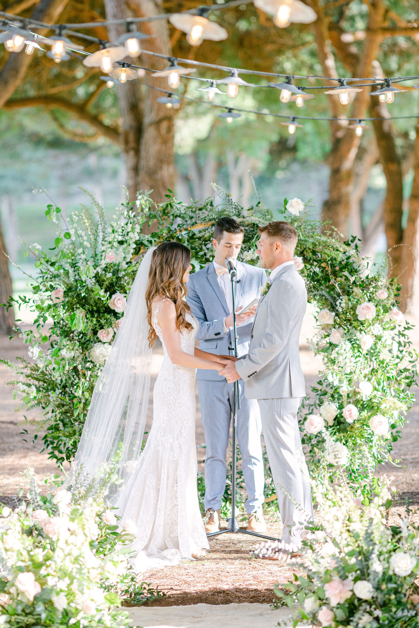 Vows beneath a greenery and white floral arch
