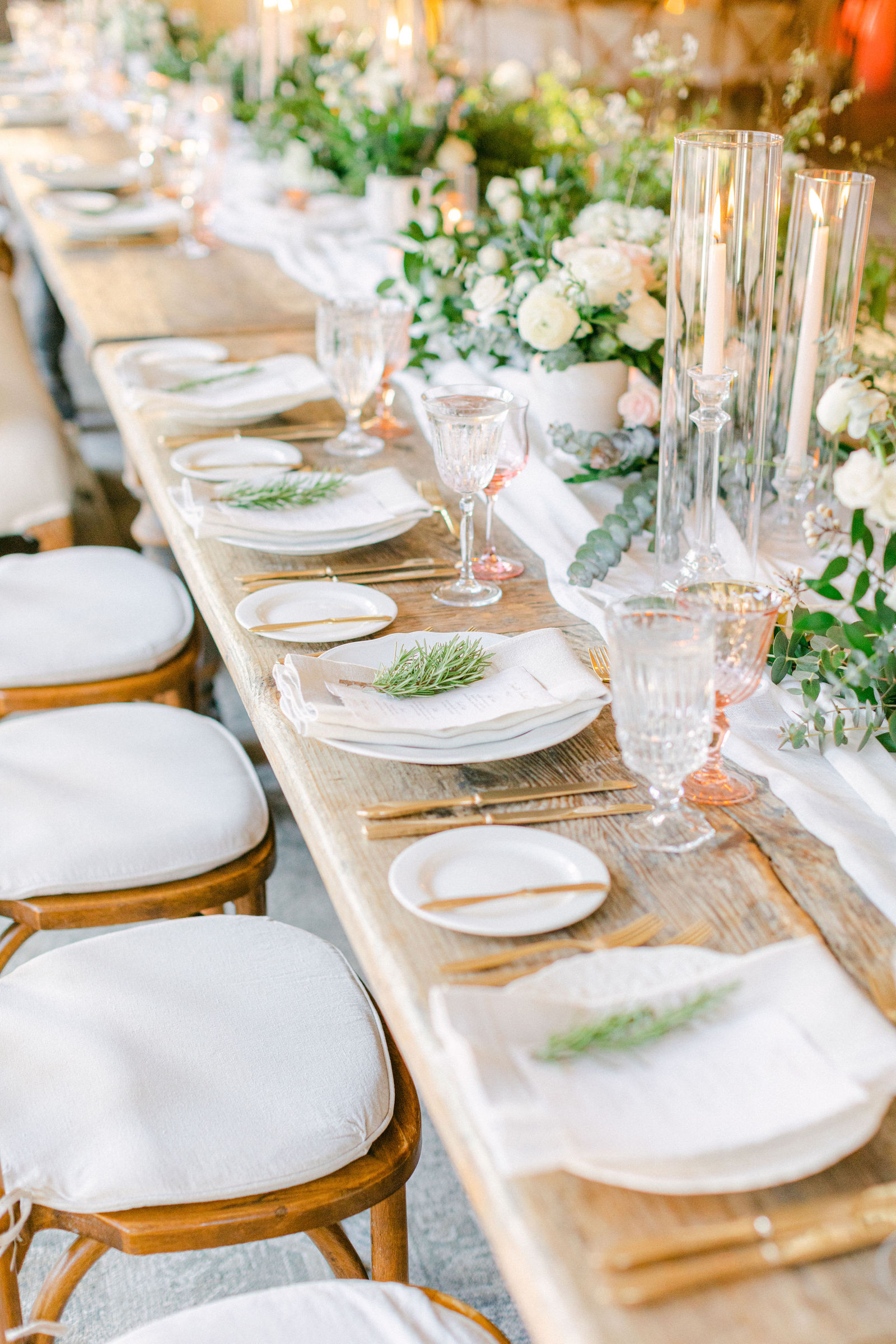 The tables set with gold flatware, greenery and candlelight