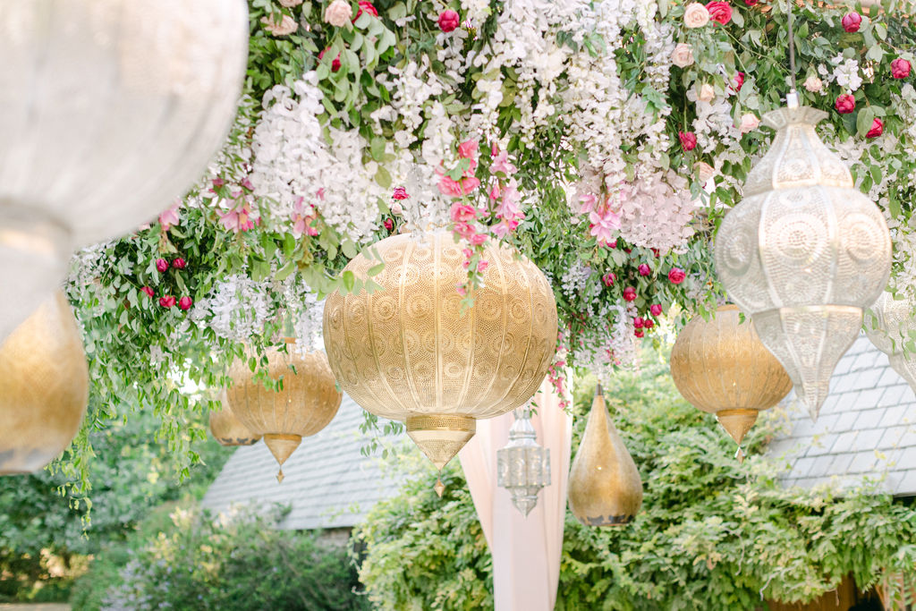 Woven gold pendant lantern hanging in a canopy of wisteria