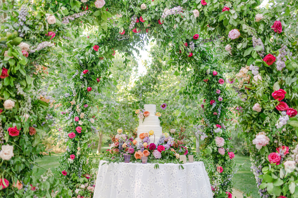 Wedding cake table framed by the rose-covered arch in the allee