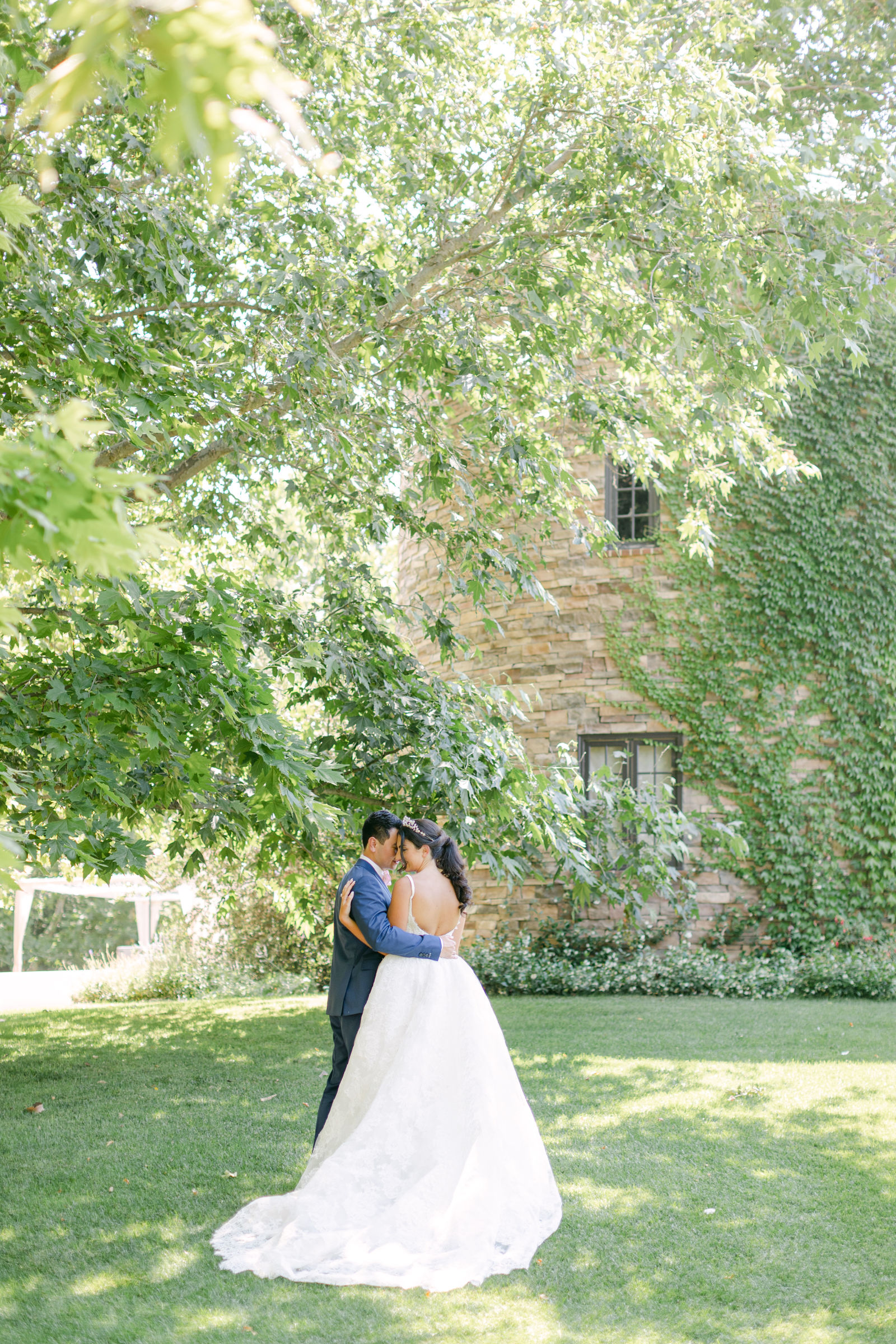 An embrace beneath the sycamore at Kestrel Park, the ivy-covered stone tower behind