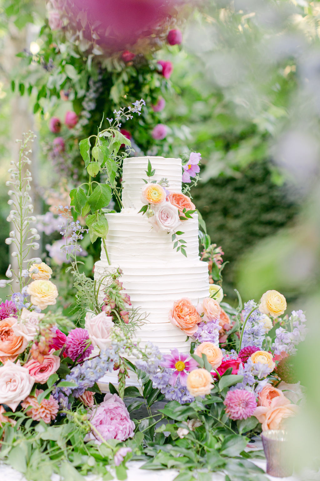 White wedding cake surrounded by garden roses and dahlias