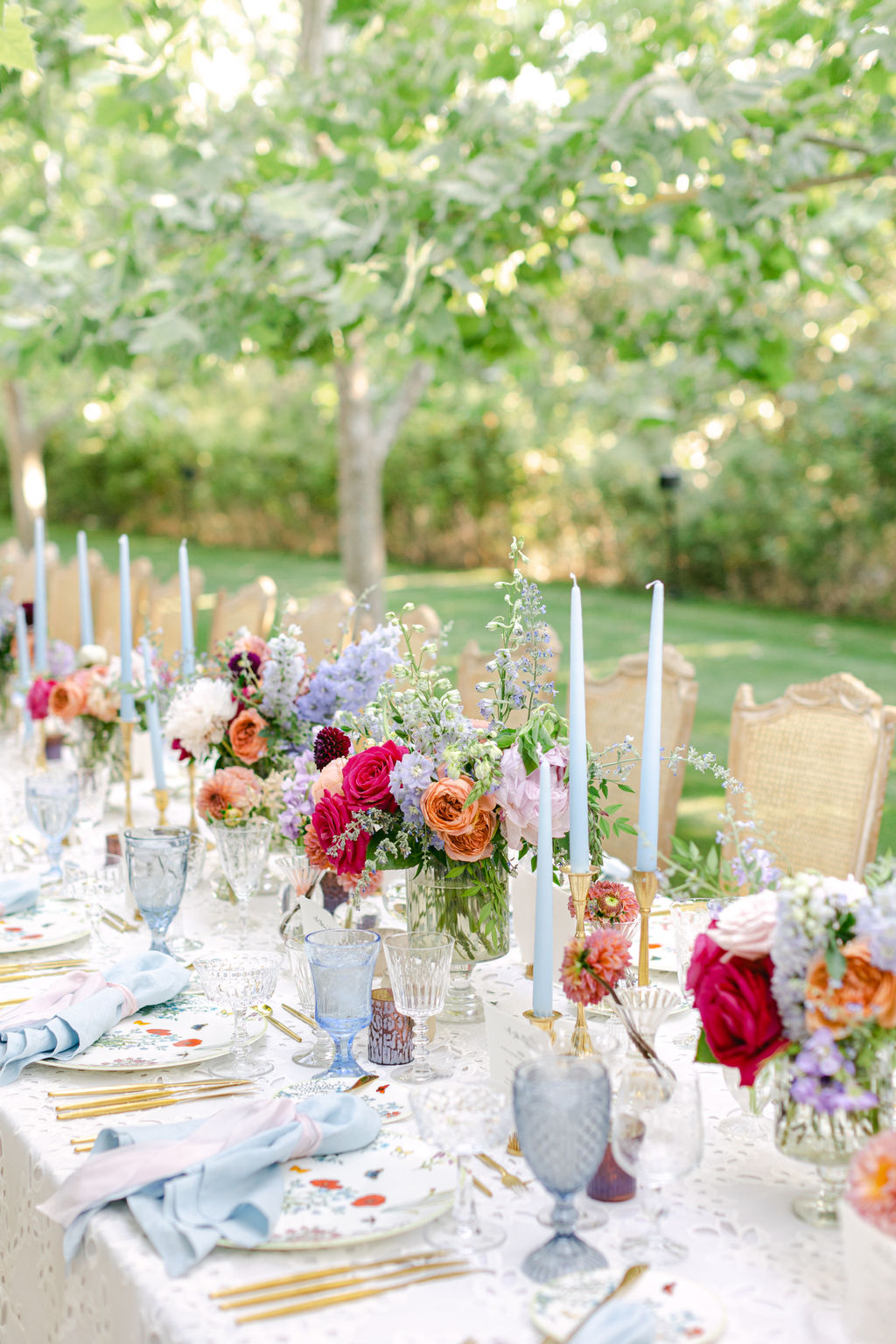 Dusty blue tapers and summer blooms down the center of the table