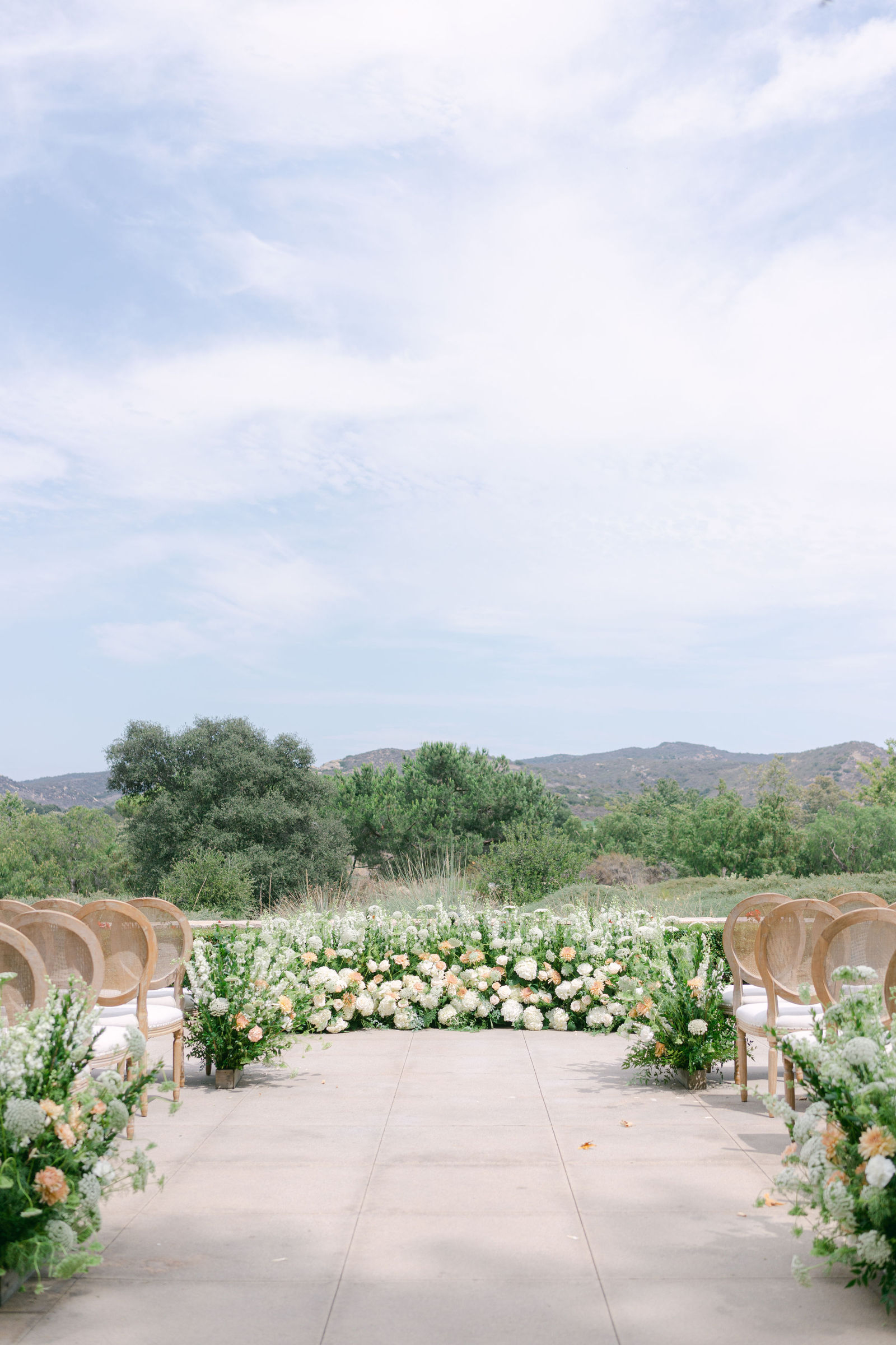 The ceremony set on the terrace at Shady Canyon Golf Club, white chairs in curved rows above the canyon