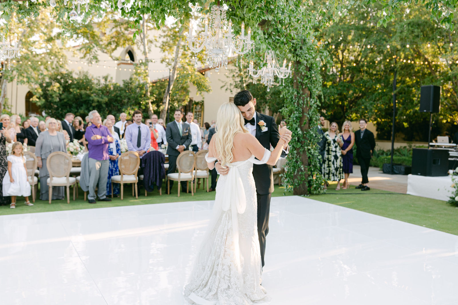 The first dance under the chandeliers, guests gathered around the floor