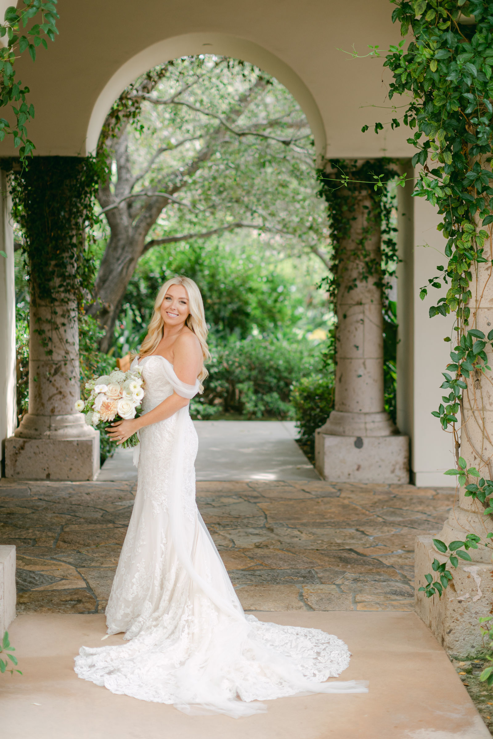 The bride in the vine-covered arched loggia at Shady Canyon Golf Club, her train across the flagstone