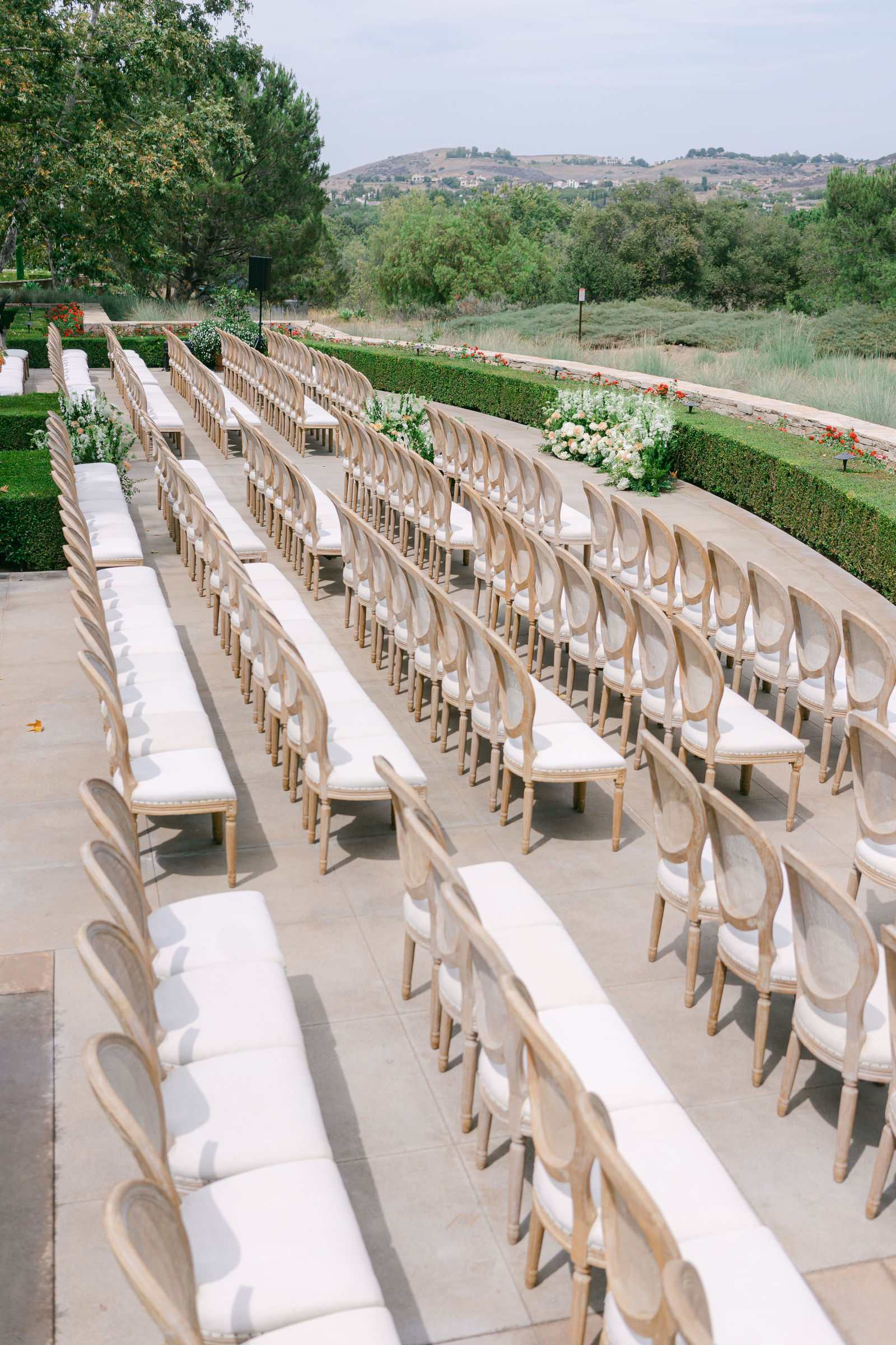 The ceremony set on the terrace at Shady Canyon Golf Club, white chairs in curved rows above the canyon