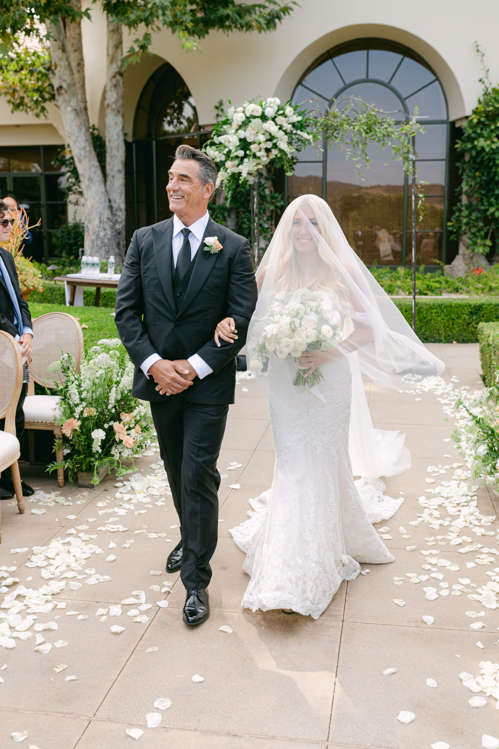 Her father walking her up a petal covered aisle, veil over her face