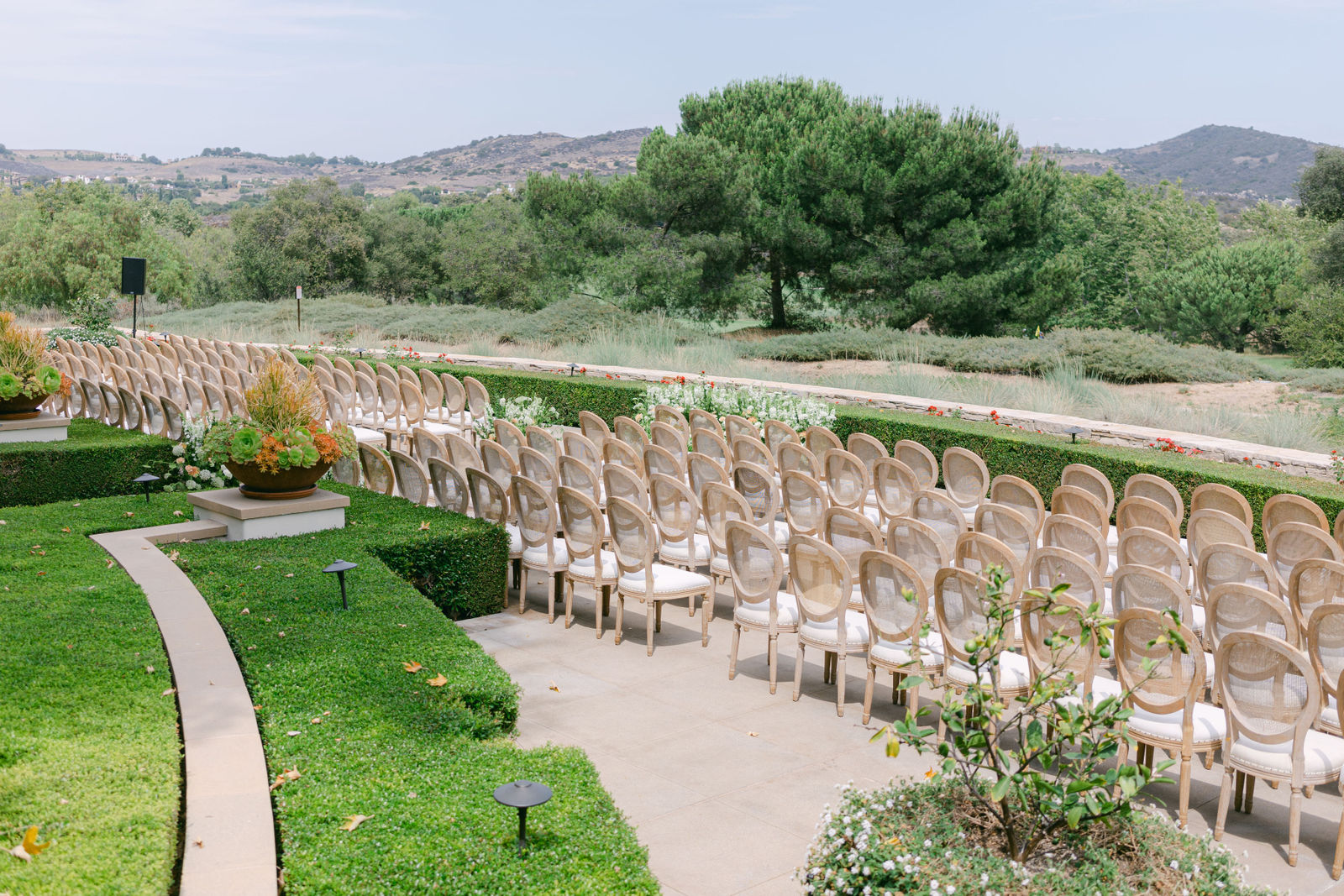 The ceremony set on the terrace at Shady Canyon Golf Club, white chairs in curved rows above the canyon
