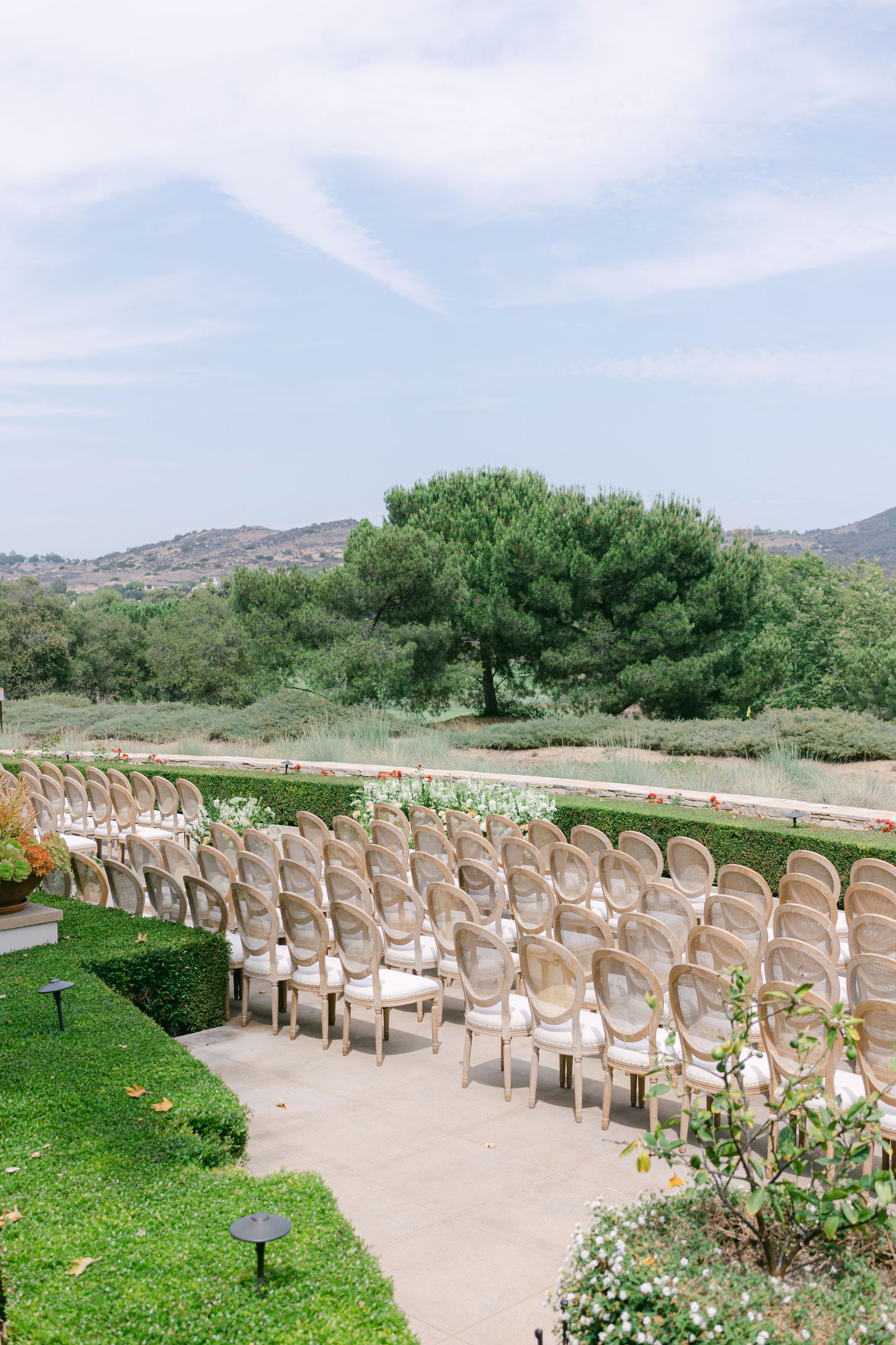 The ceremony set on the terrace at Shady Canyon Golf Club, white chairs in curved rows above the canyon