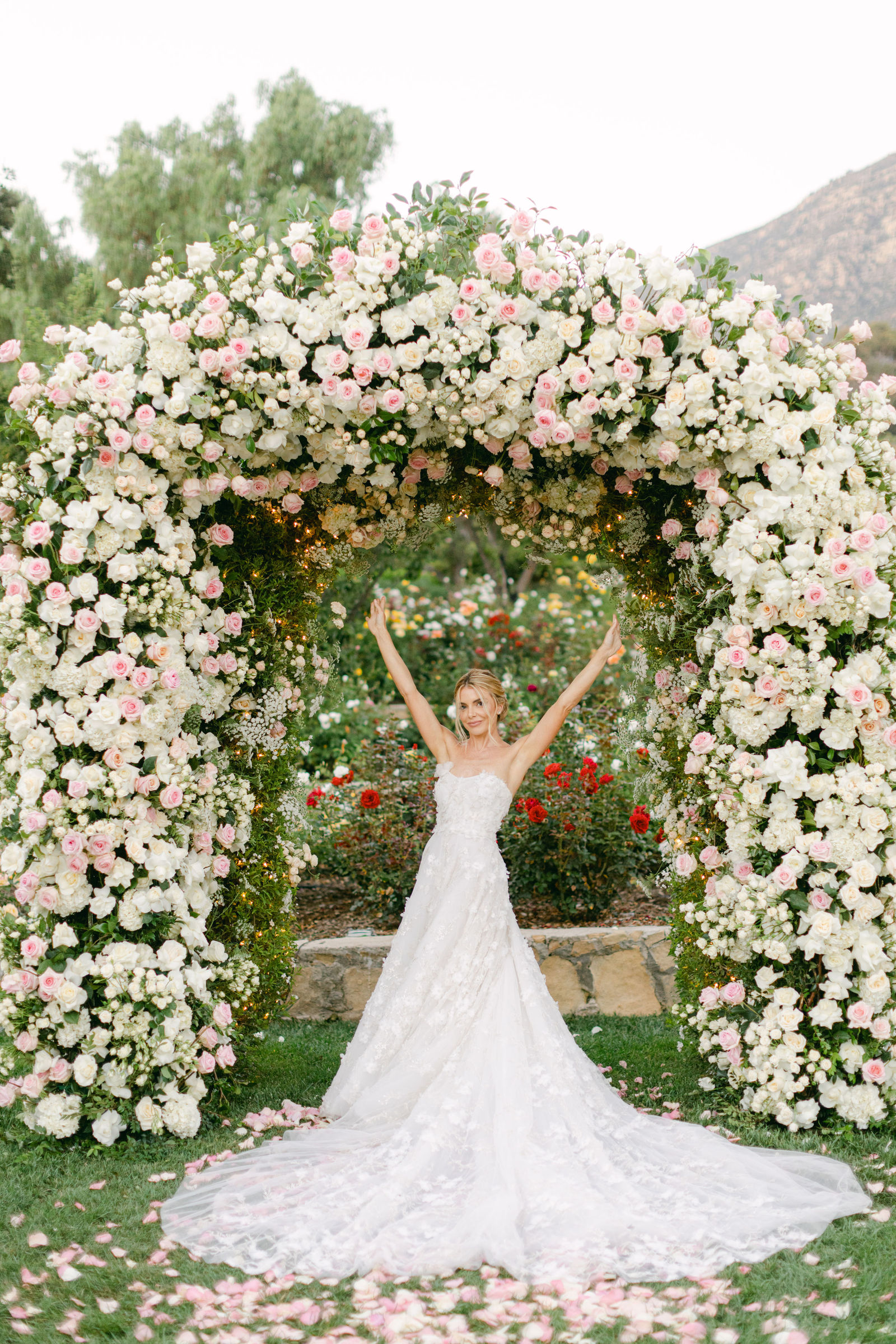 Sofia, arms up beneath the rose arch at San Ysidro Ranch