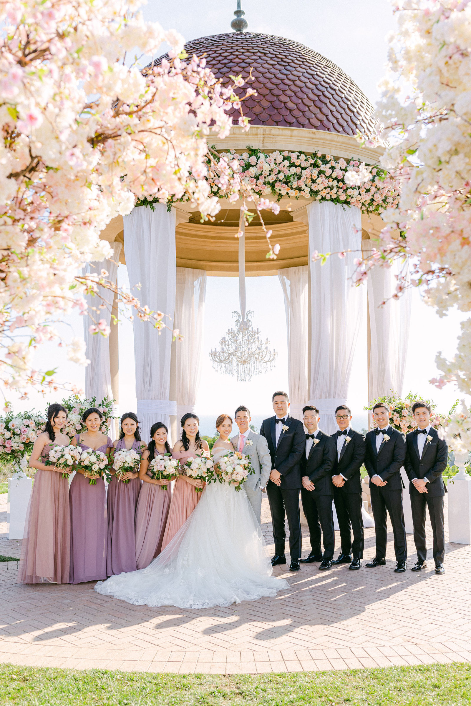 The full bridal party beneath the flower-wrapped rotunda at Pelican Hill