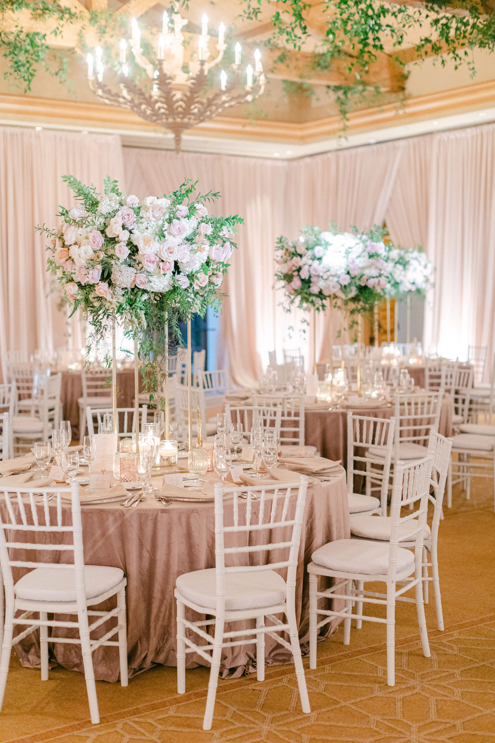 The Pelican Hill ballroom in blush, chandeliers above tall floral centerpieces