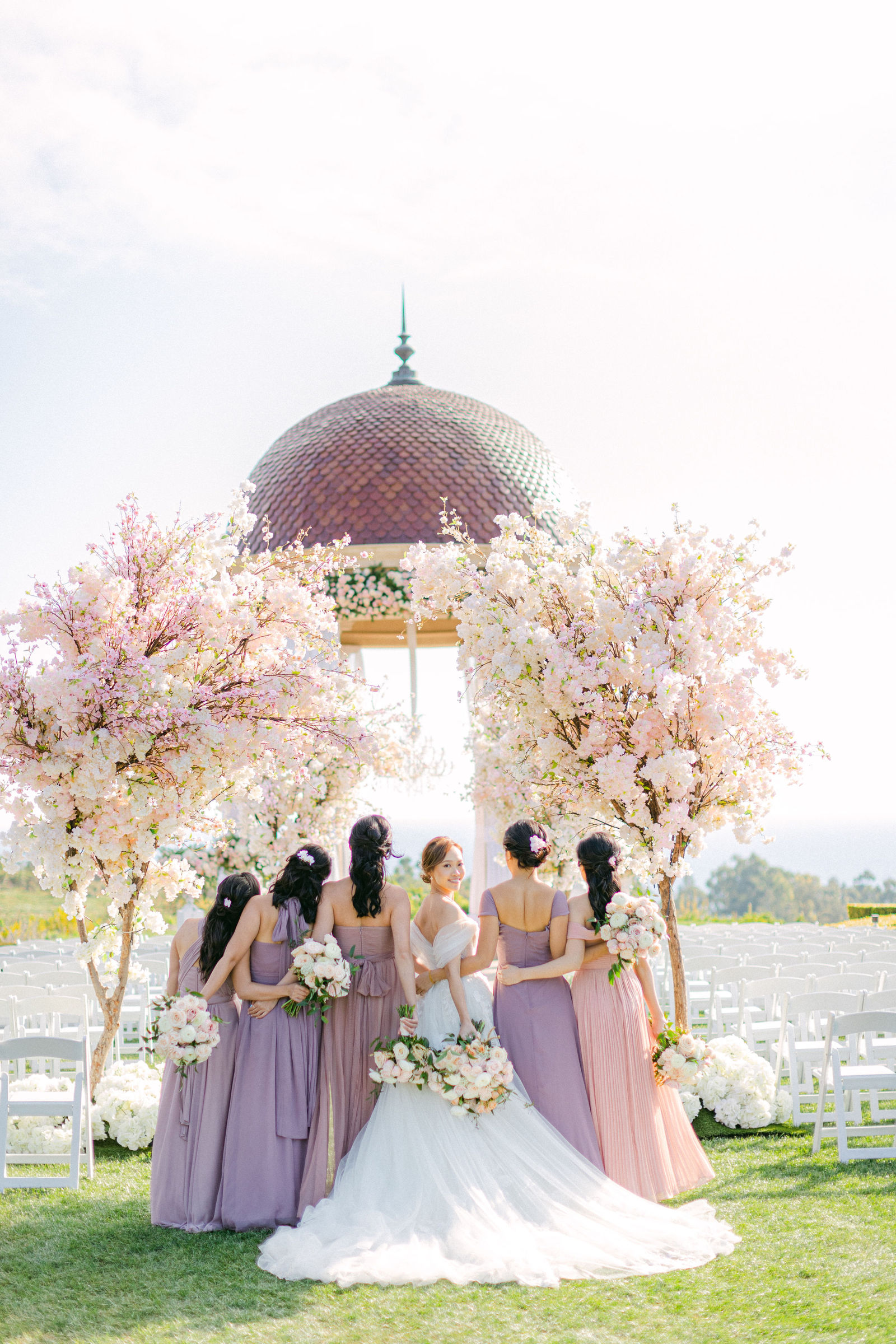 Bridesmaids in lilac and mauve with the bride, the Pacific in front of them