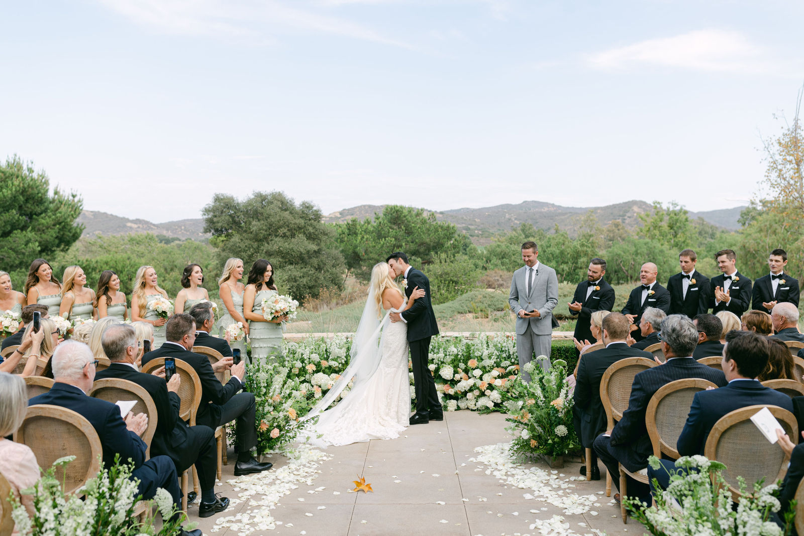 The kiss at the ceremony on the terrace at Shady Canyon Golf Club, the canyon behind them