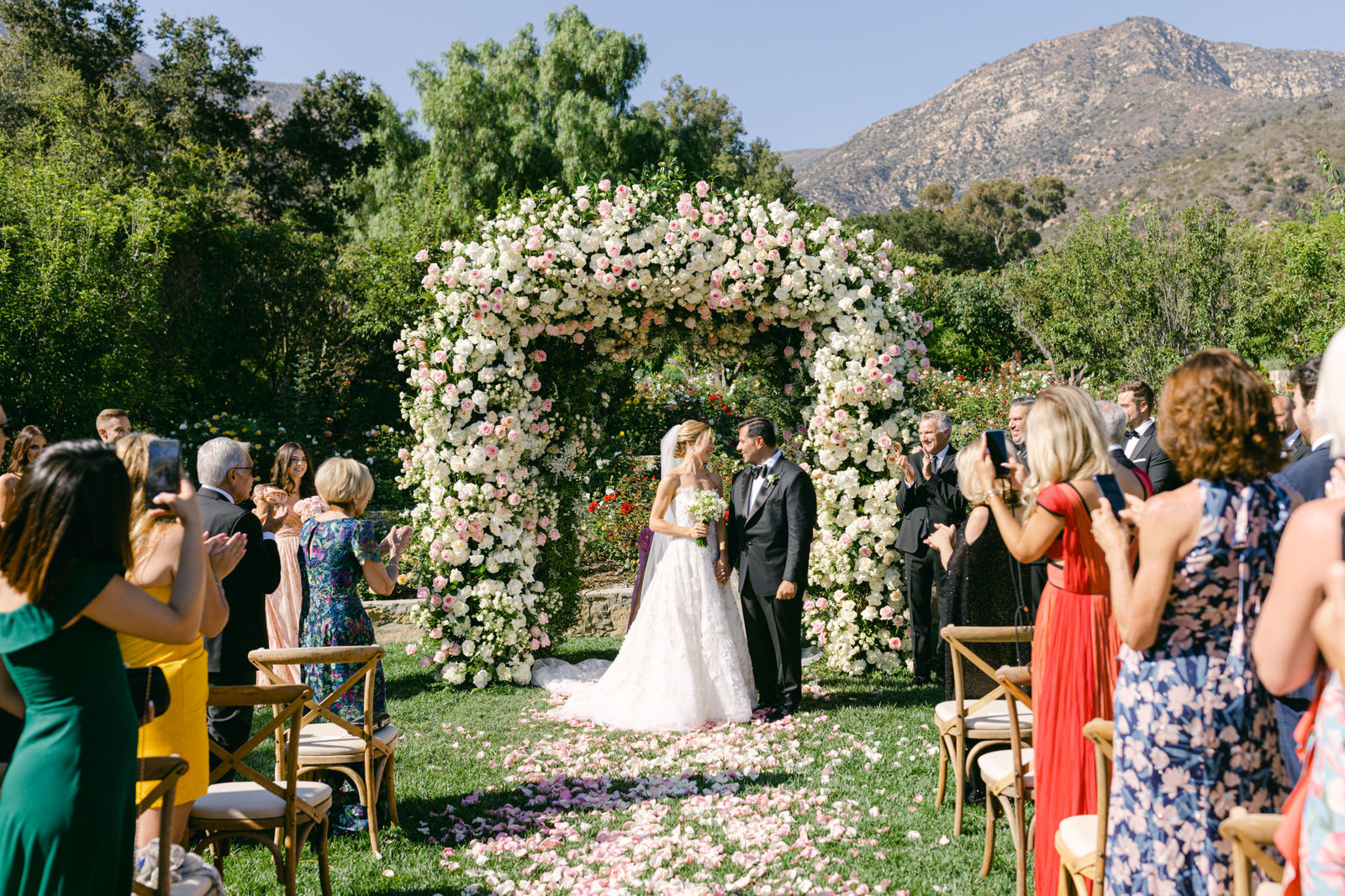 Sofia and Marc exchanging vows beneath the rose arch at San Ysidro Ranch