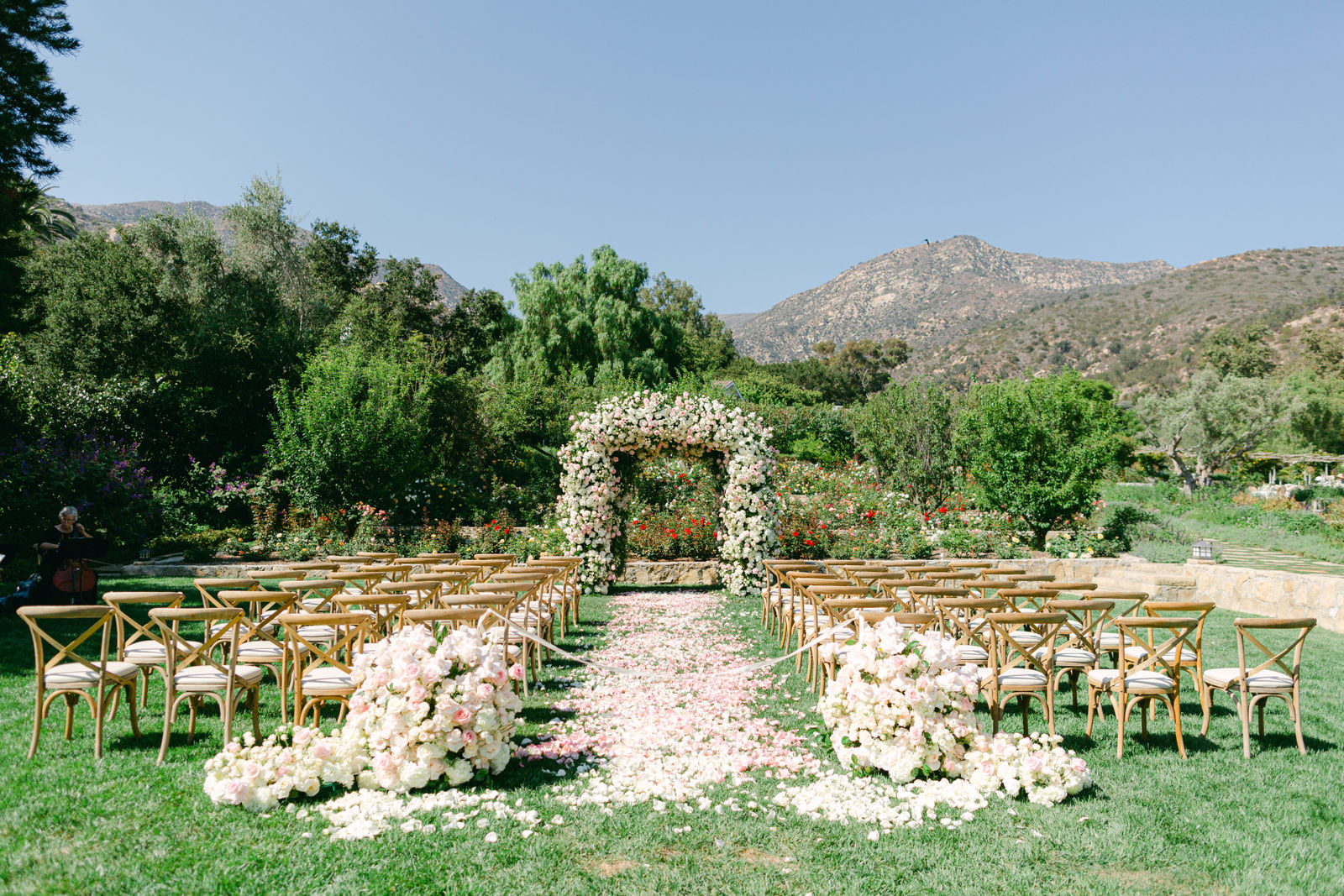 The rose garden ceremony site at San Ysidro Ranch, a petal aisle and the Montecito mountains beyond